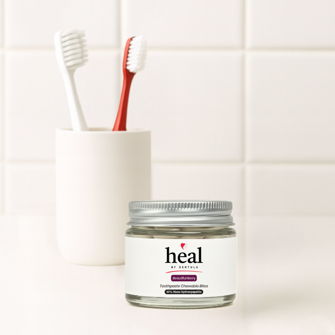 Jar of 'heal' toothpaste with a cup and toothbrush on a tiled bathroom wall background