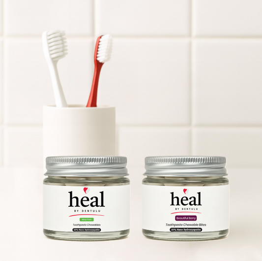 Two jars labeled 'heal' with a toothbrush holder containing a red toothbrush on a white tiled wall background.